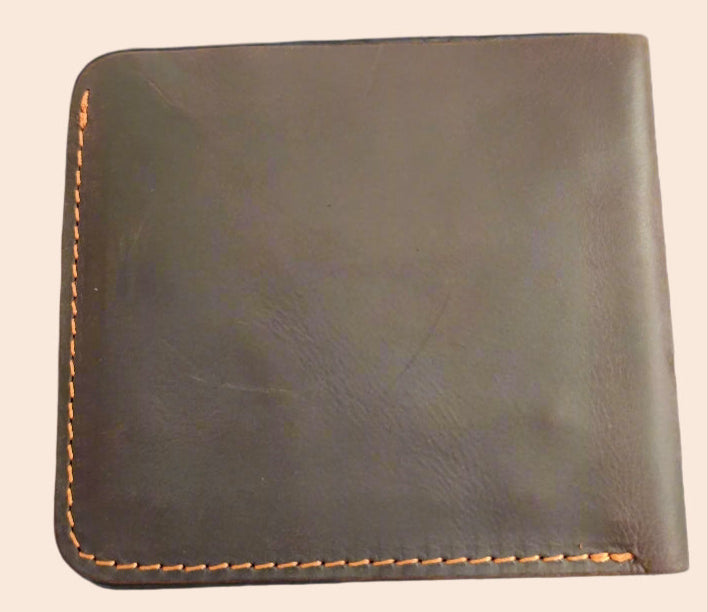 Brown leather wallet held by a hand with a blurred background
