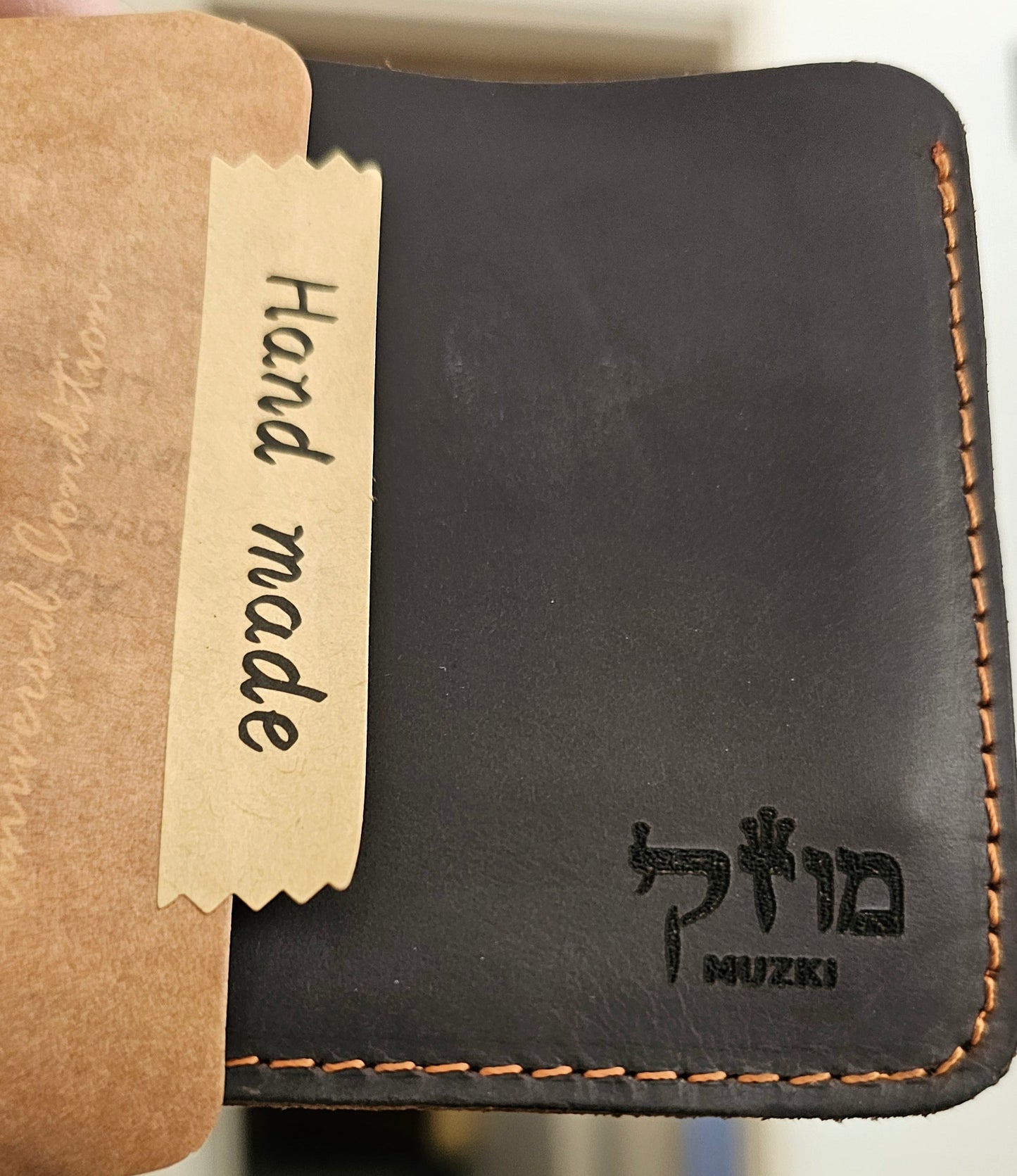 Black leather wallet with 'Mizuki' branding and a 'Hand made' label on a blurred background