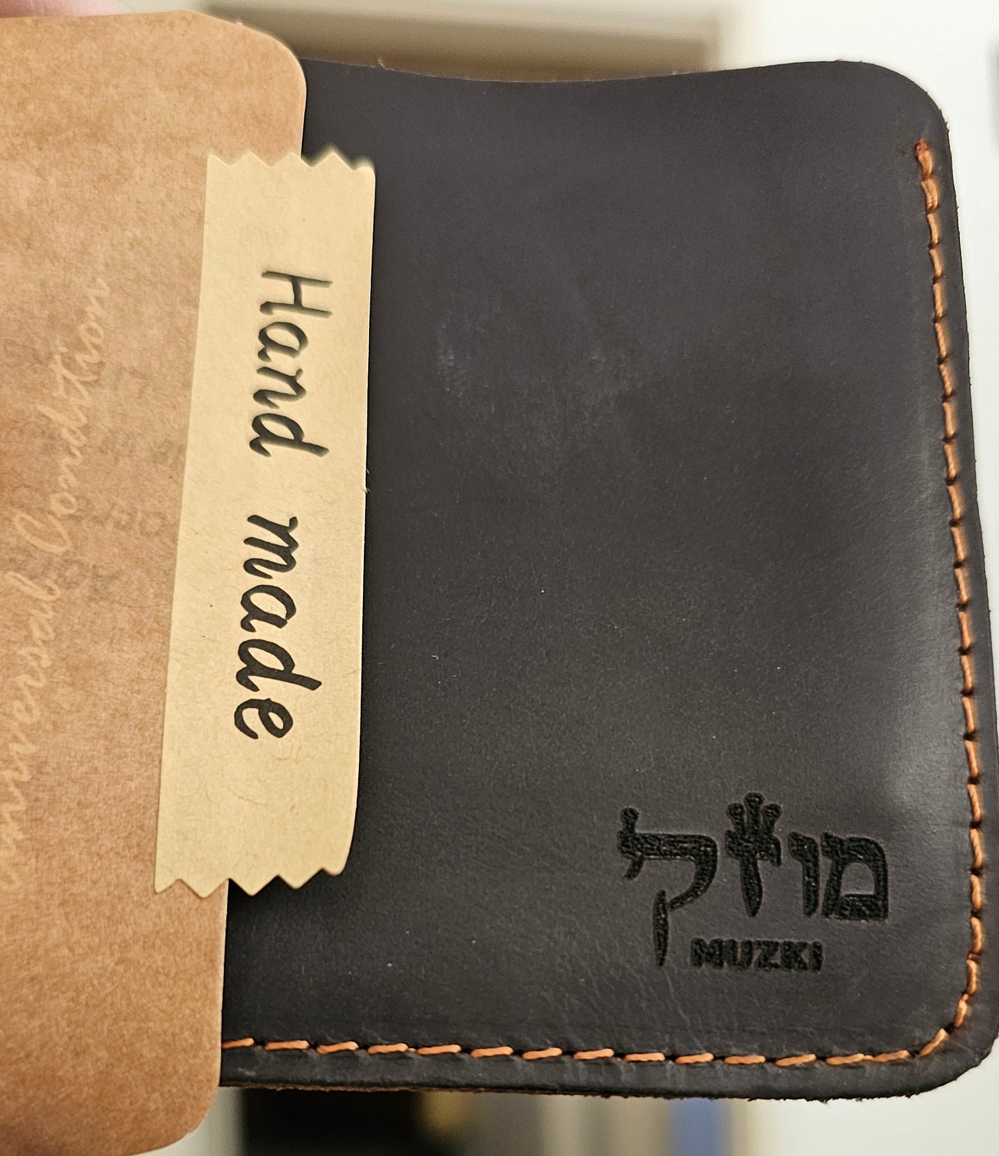 Black leather wallet with 'Mizuki' branding and a 'Hand made' label on a blurred background