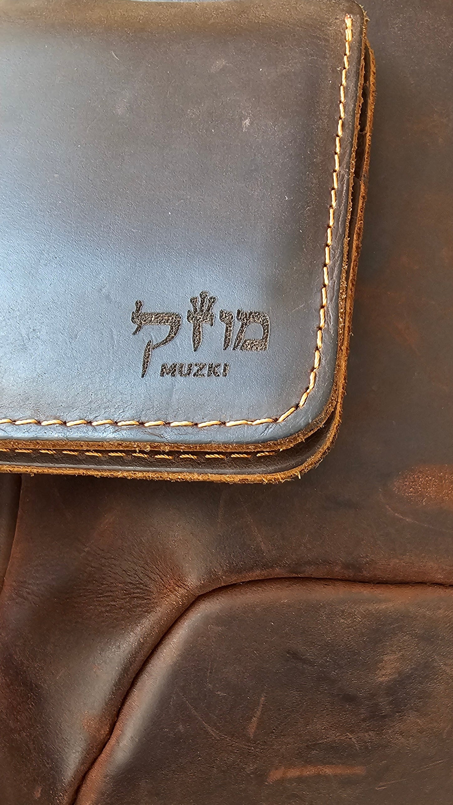 Brown leather bag with 'Muziki' branding on a beige background