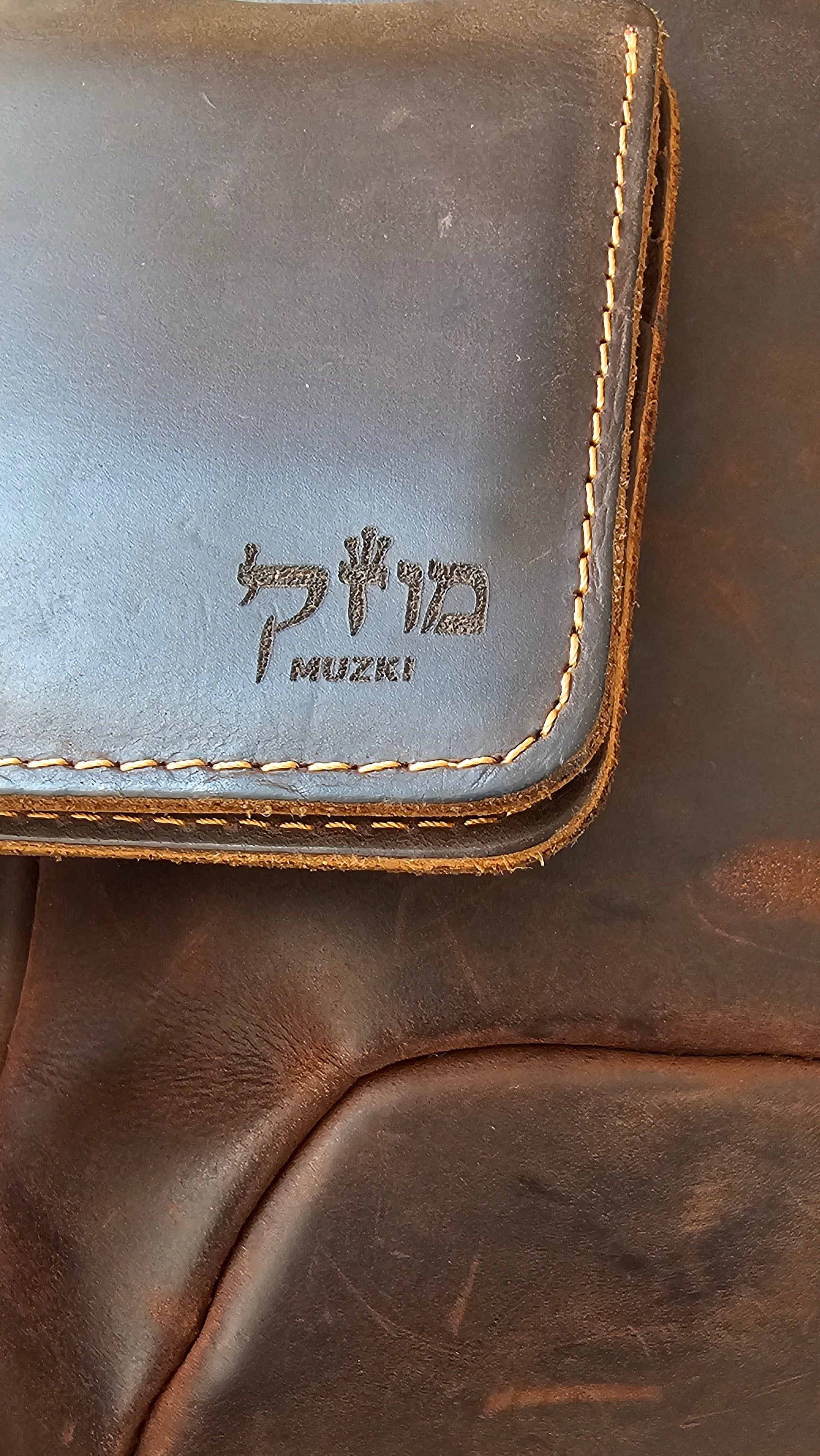 Brown leather bag with 'Muziki' branding on a beige background